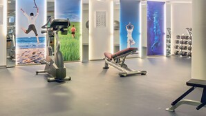 A gym with exercise equipment, posters on the walls, and a mirror reflecting the space. - Scandic Sønderborg (Sønderborg)