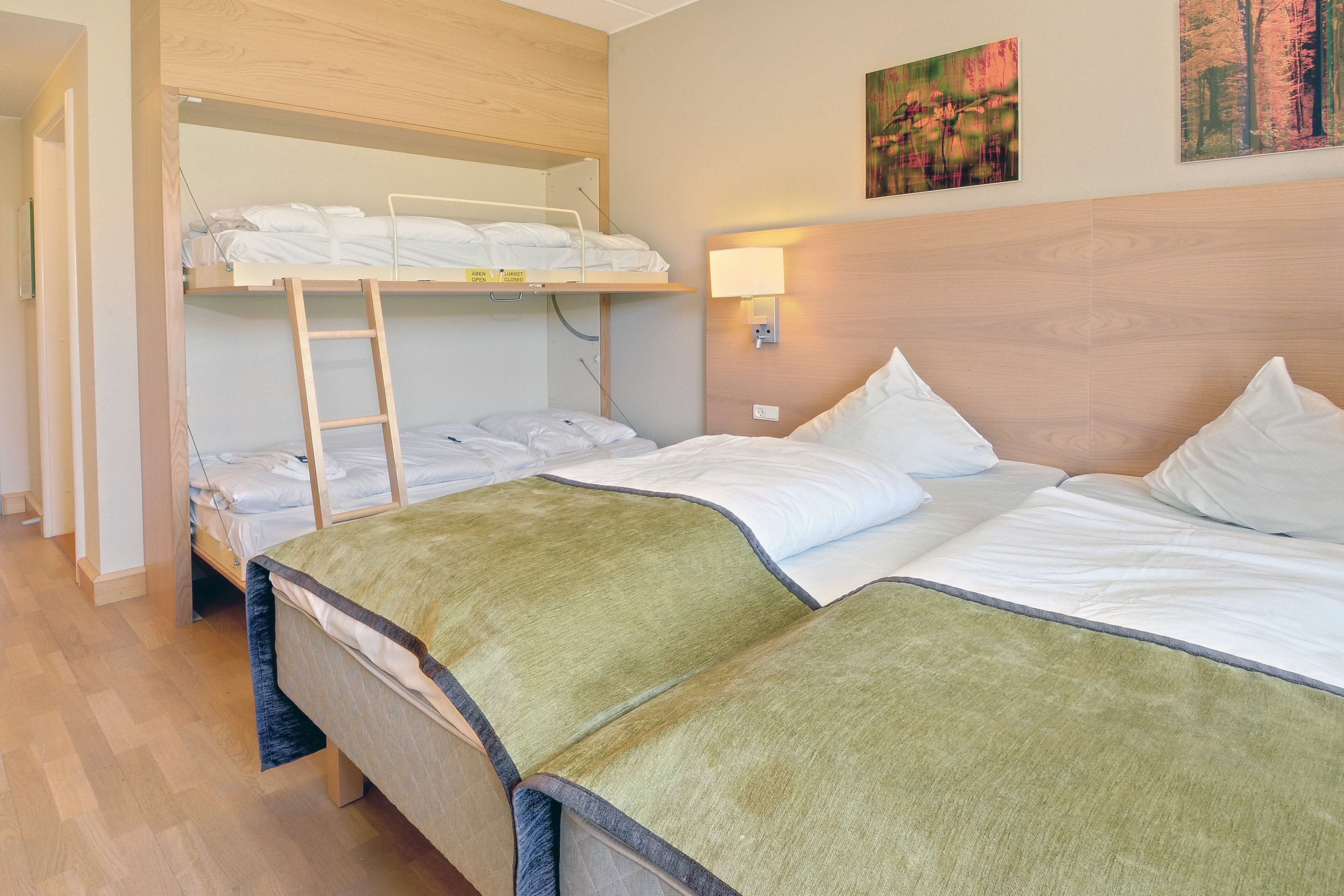 Une chambre d’hôtel avec un lit superposé, un lit simple et une table de chevet avec une lampe.