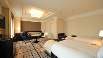 Habitación de hotel con dos camas, un escritorio, una silla, un televisor y una alfombra estampada.