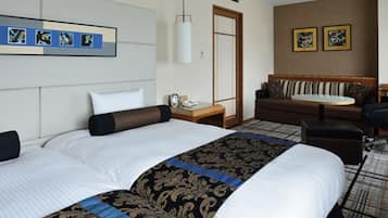 Quarto de hotel com uma cama grande, uma escrivaninha, uma cadeira, um sofá e uma mesinha.