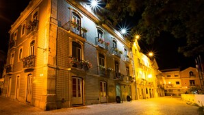 A historic building with multiple balconies, large windows, and a cobblestone street at night. - Hotel Solaris (Setubal)