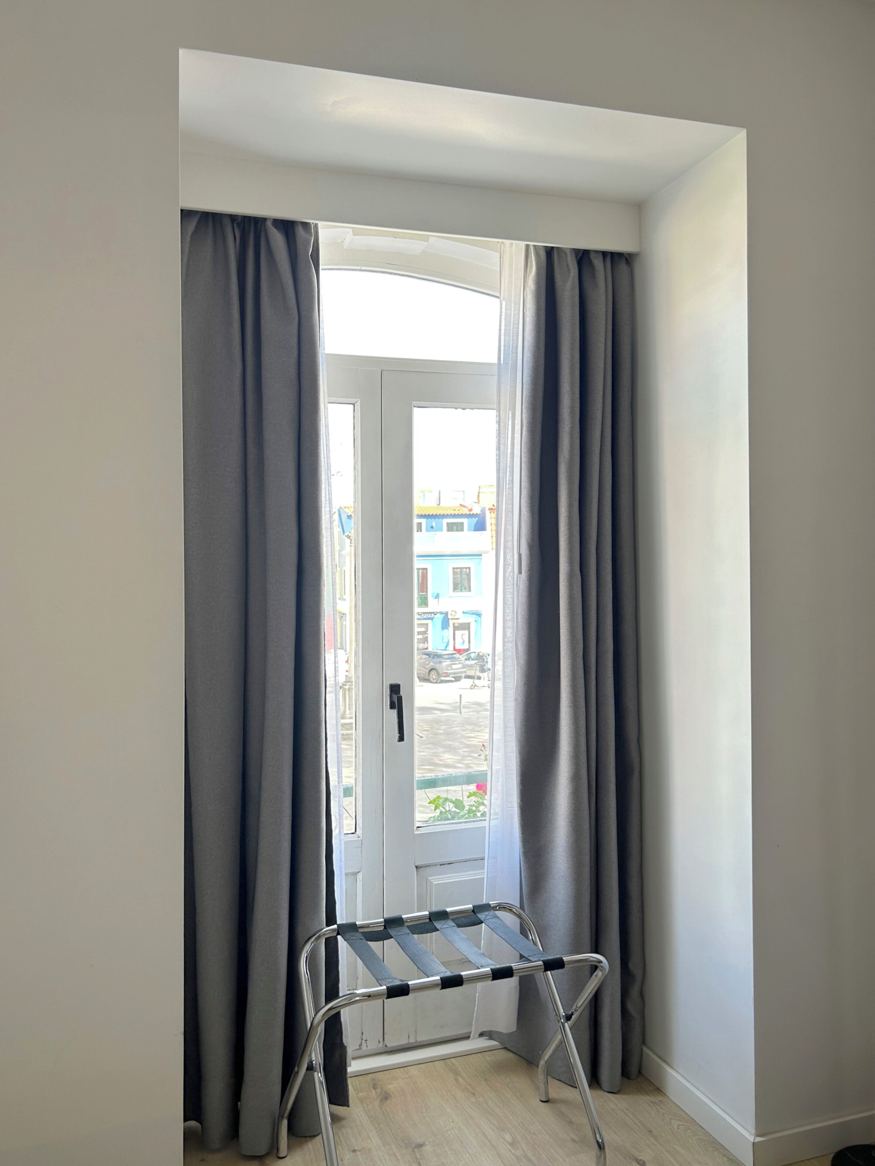 Una habitación con una puerta que da a un espacio exterior, un tendedero metálico y vistas de edificios.
