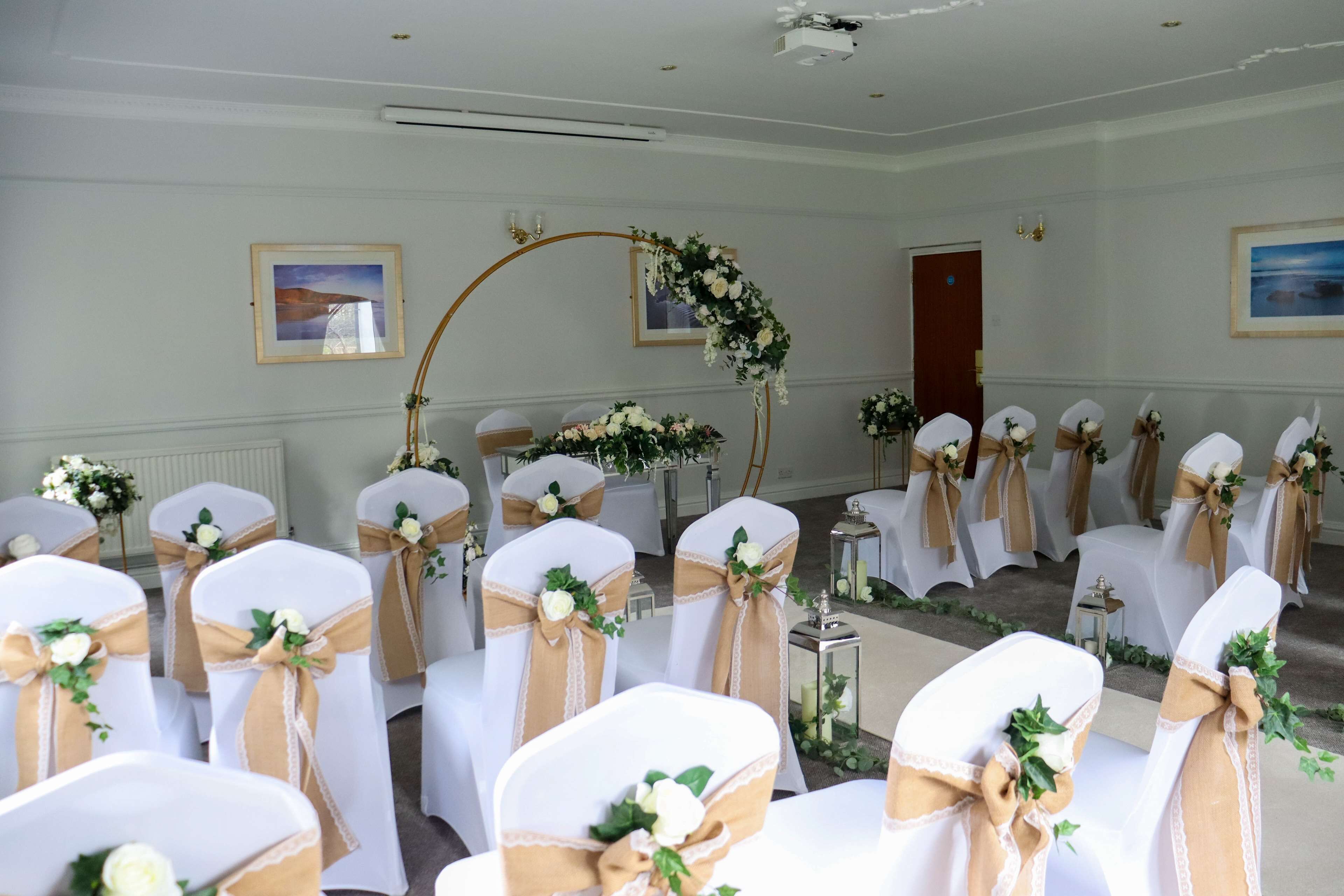 A wedding ceremony setup with rows of chairs, floral decorations, and a wooden arch.