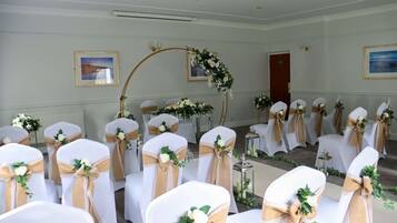 A wedding ceremony setup with rows of chairs, floral decorations, and a wooden arch.