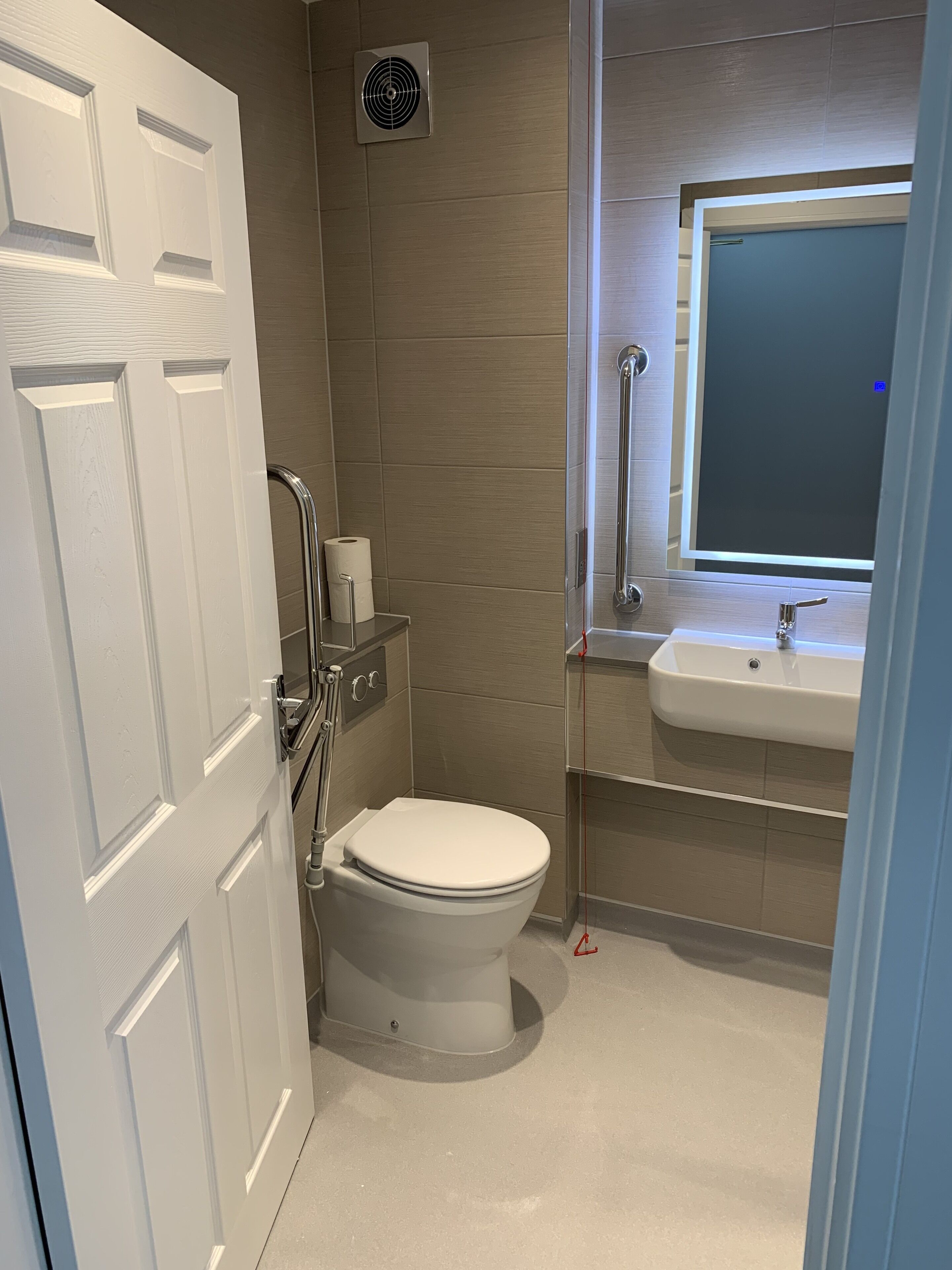 Un baño moderno con inodoro, secamanos, espejo y lavabo.