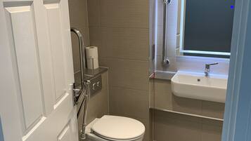 Un baño moderno con inodoro, secamanos, espejo y lavabo.