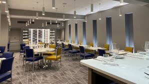 A modern dining area with tables set for service, overhead lighting, and a patterned floor. - Best Western Premier Heronston Hotel & Spa (Bridgend)