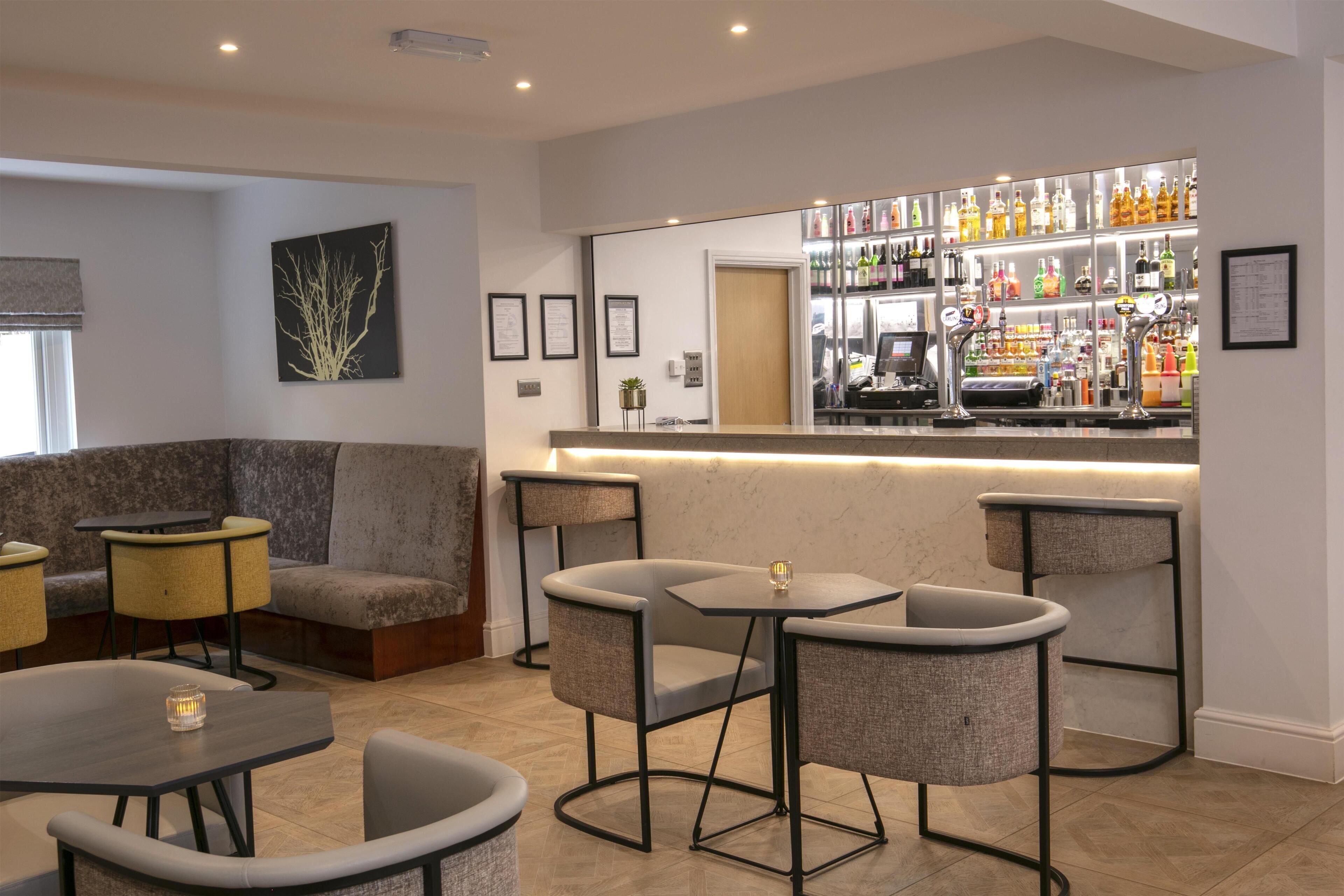 A bar area with a counter, seating, and a display of liquor bottles.