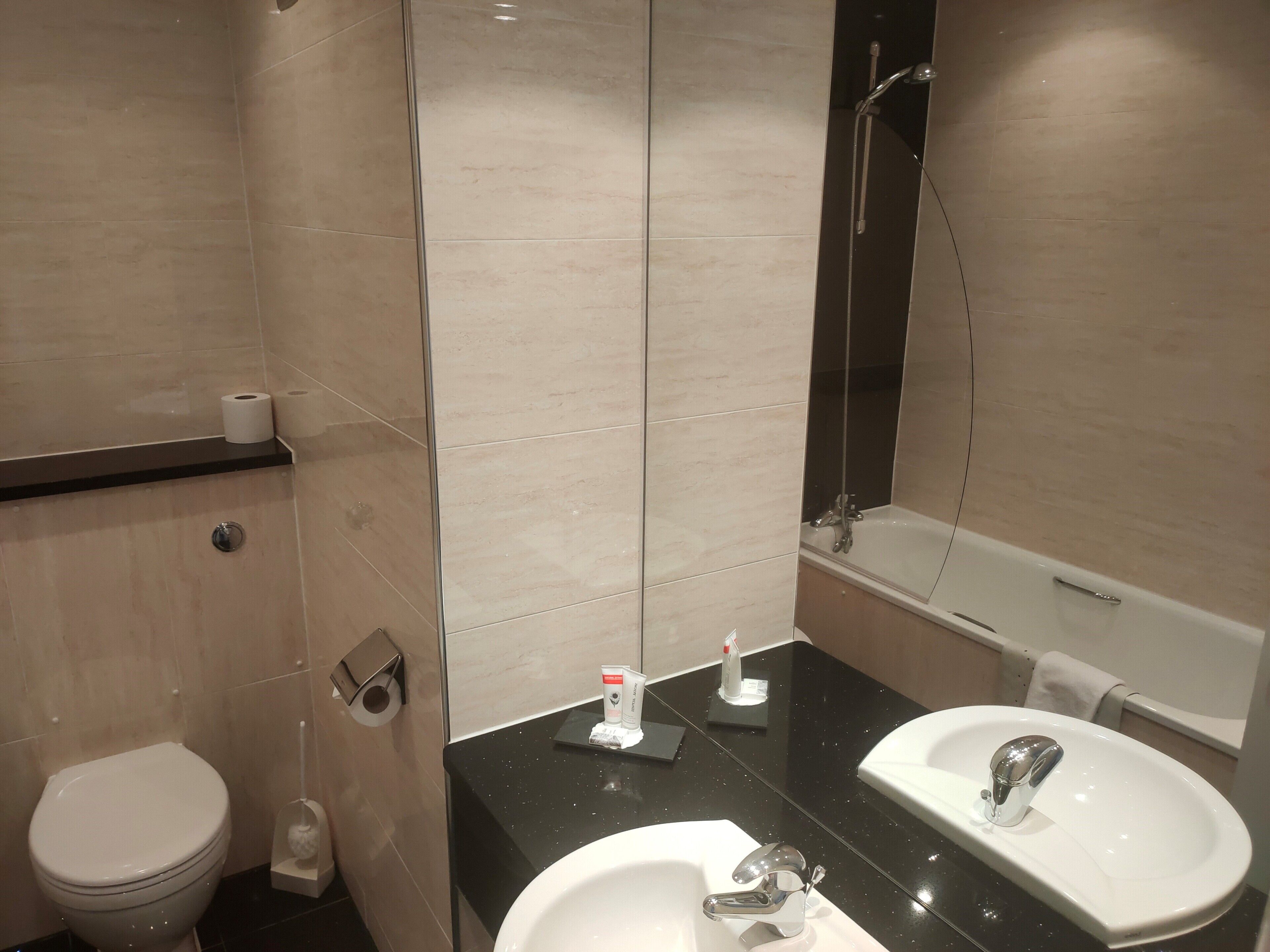 A modern bathroom with a toilet, sink, and bathtub.