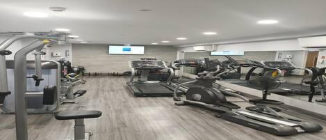 A gym with treadmills, elliptical machines, and weightlifting equipment.