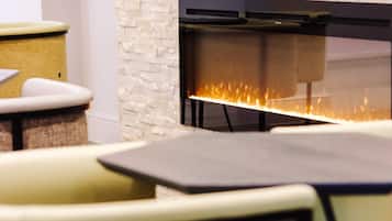 A modern interior with a stone fireplace, seating area, and a flat-screen TV mounted above the fireplace.