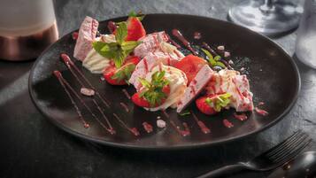Un plato con fresas, menta y chocolate sobre un plato oscuro.