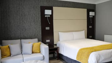 A hotel room with a bed, a sofa, and a small table.