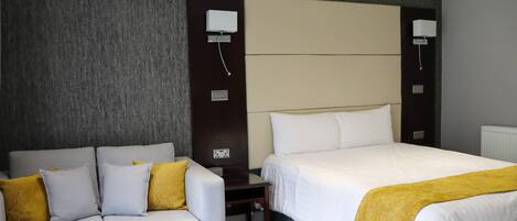 A hotel room with a bed, a sofa, and a small table.
