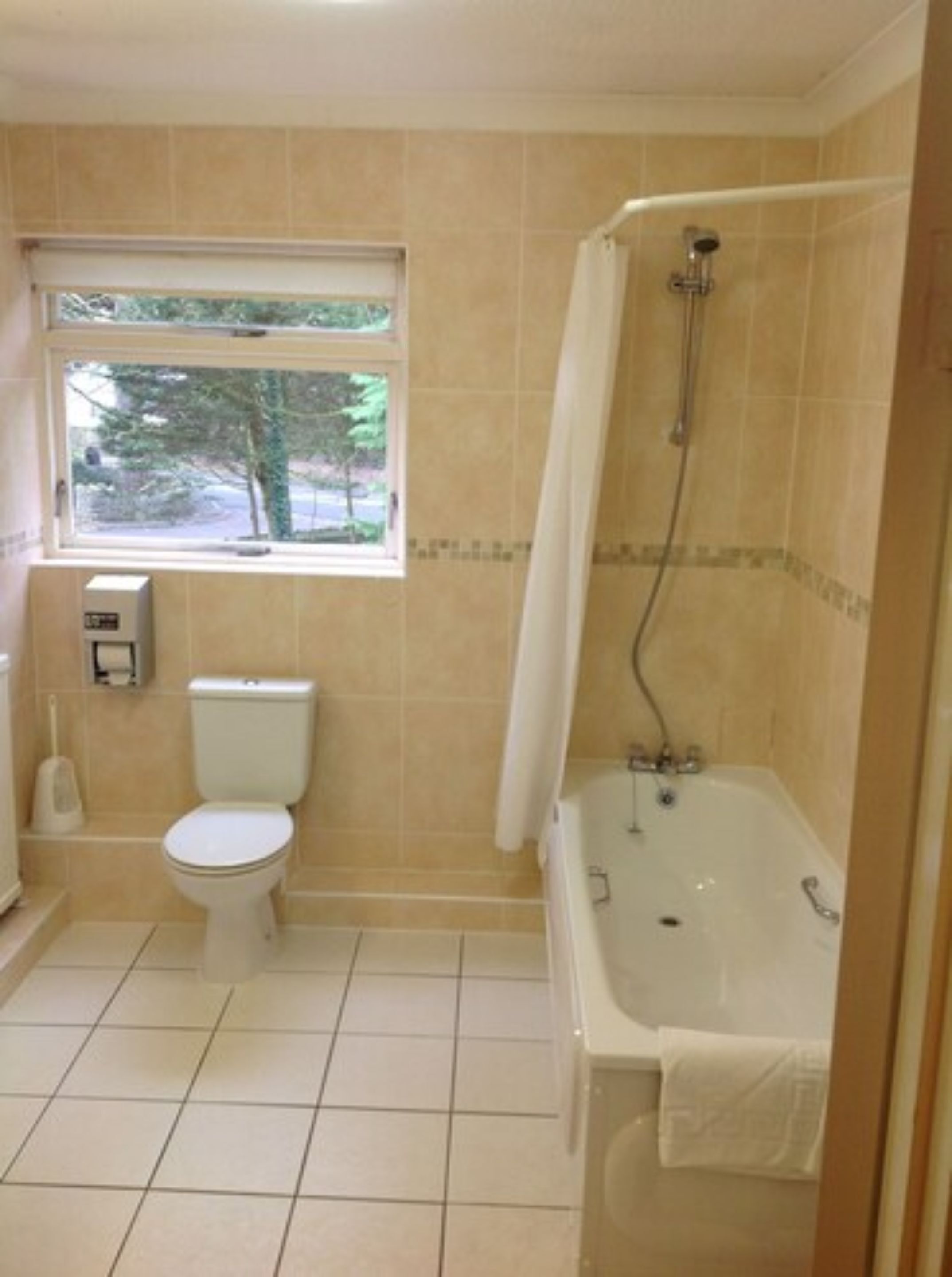 A bathroom with a toilet, a window, and a bathtub.