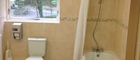 A bathroom with a toilet, a window, and a bathtub.