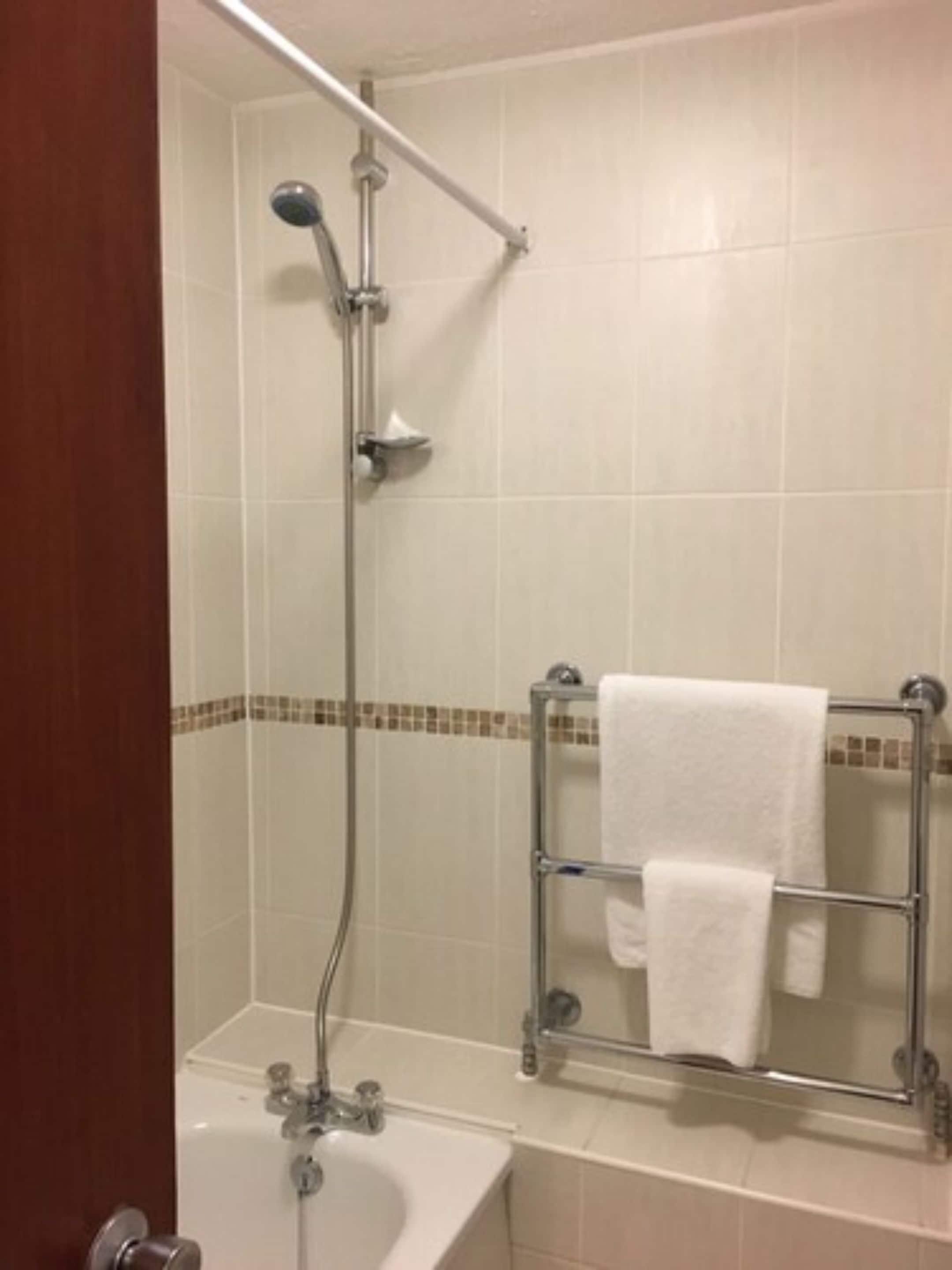A bathroom with a shower, a sink, and a towel rack.