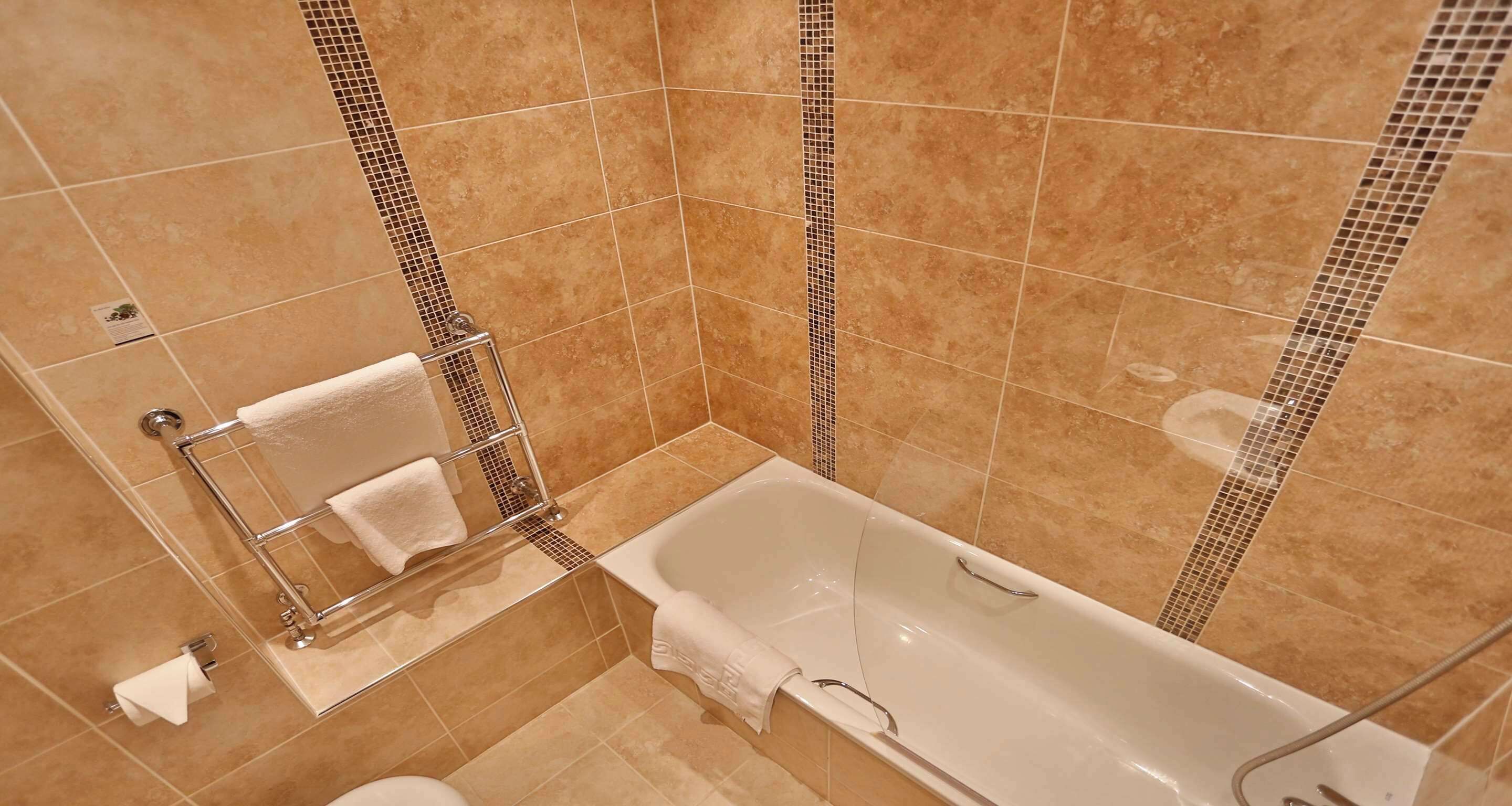 Un baño con bañera, toallero y retrete.