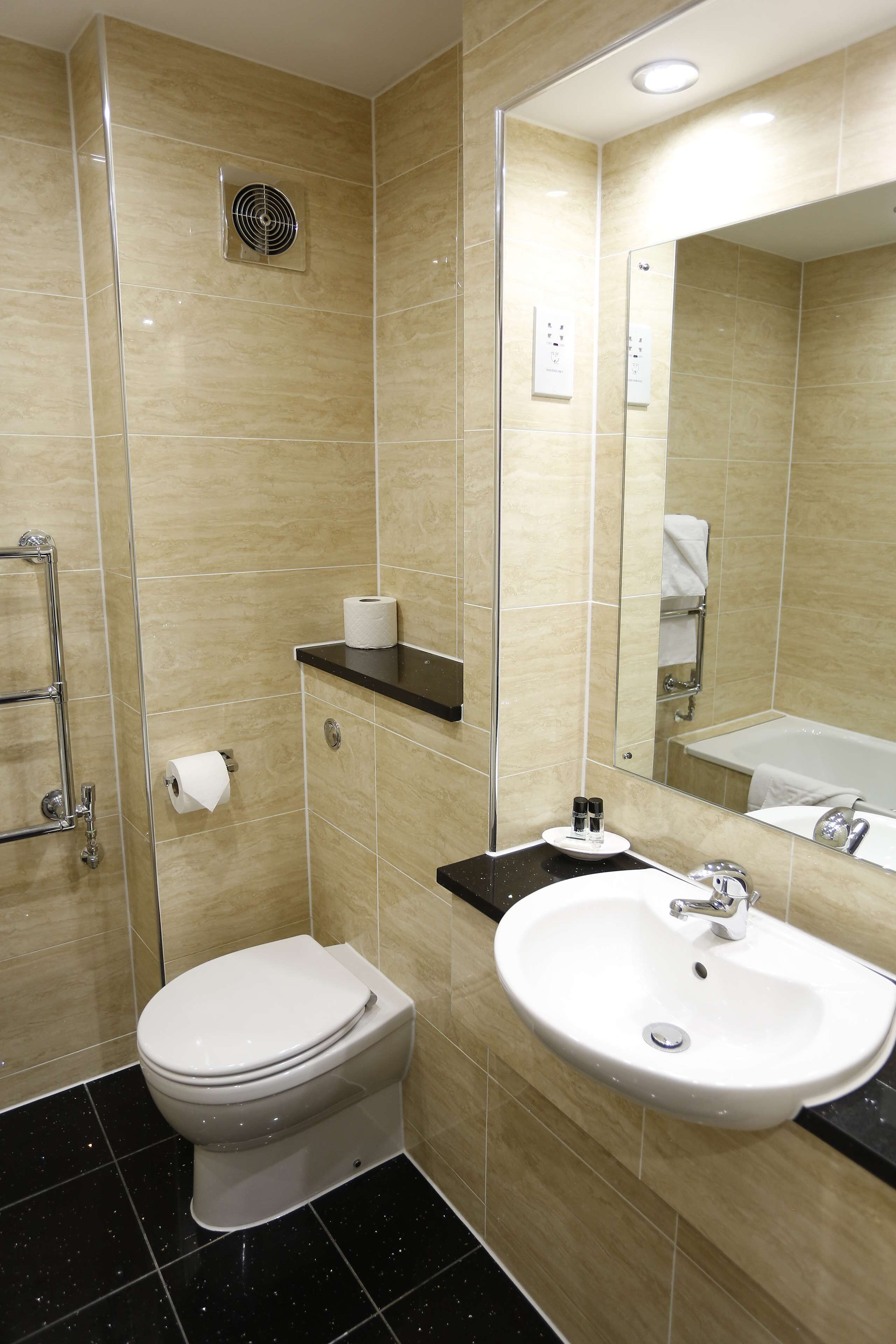A modern bathroom with a toilet, sink, and mirror.