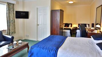 Una habitación de hotel con cama, escritorio, silla, televisor y armario.