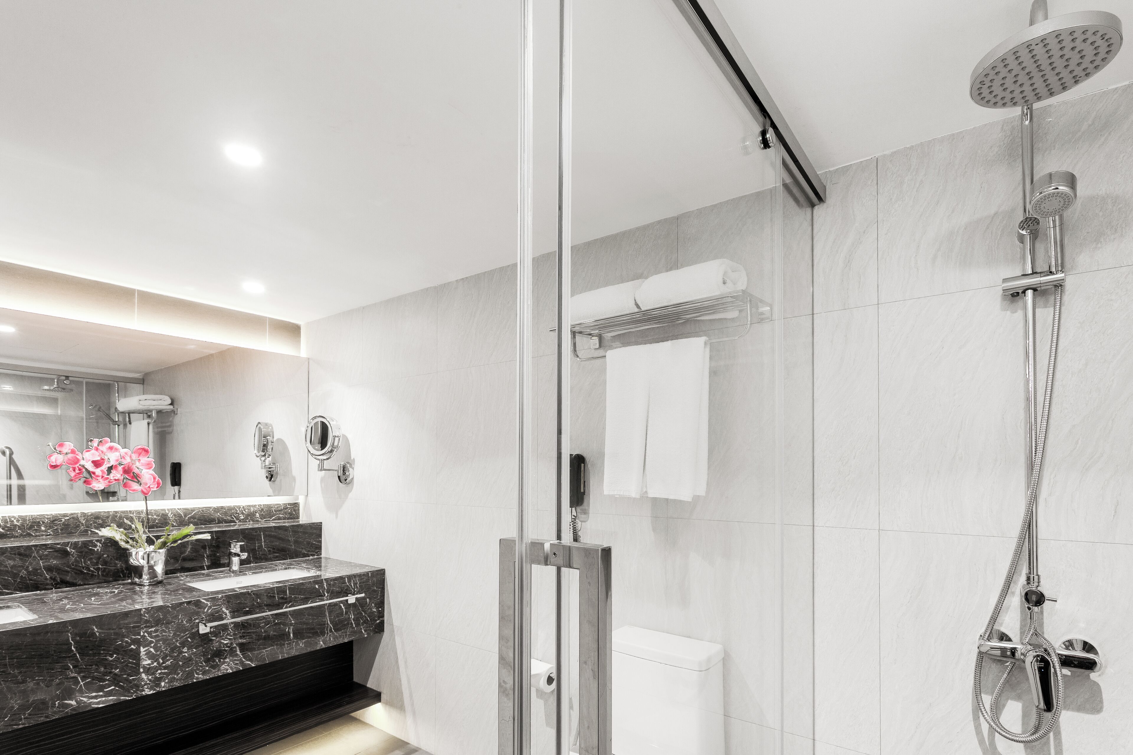 A modern bathroom with a glass-enclosed shower, a marble sink, and a toilet.
