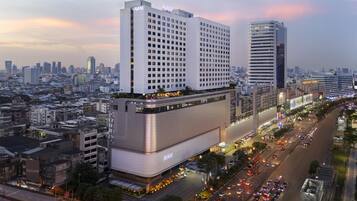 A high-rise hotel with multiple floors, a prominent 'AVANI' sign, and a busy urban street below.