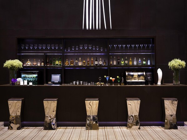 A bar area with shelves of liquor bottles, a wine cooler, and a coffee machine.