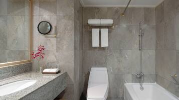 A modern bathroom with a granite countertop, a toilet, a bathtub, and a shower.