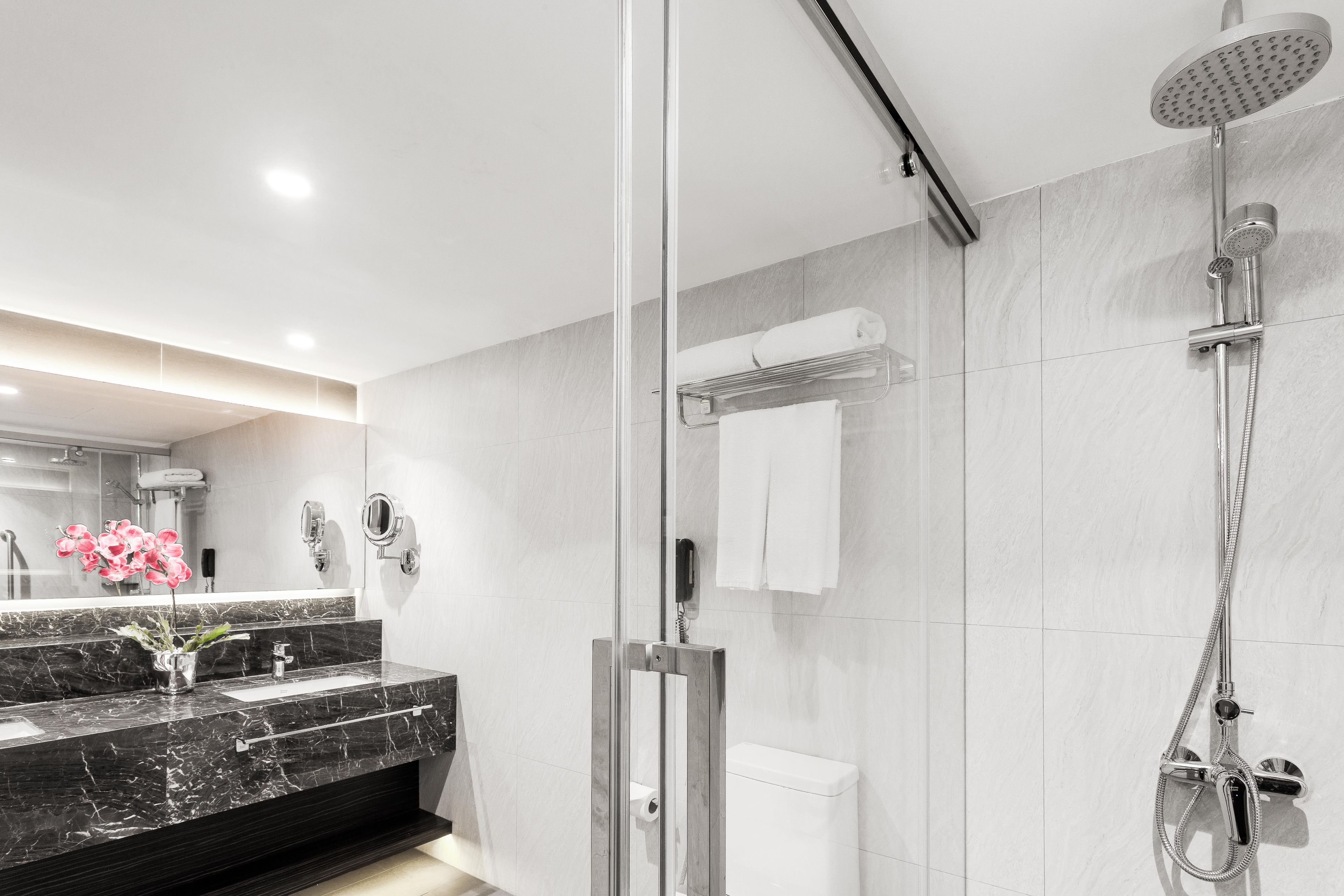 A modern bathroom with a glass-enclosed shower, a marble vanity, and a toilet.