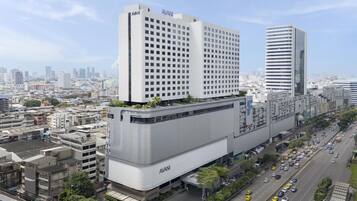 A modern hotel with a prominent 'AVANI' sign, surrounded by urban buildings and a busy street.