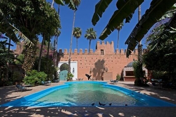 Una piscina al aire libre, sombrillas, sillones reclinables de piscina