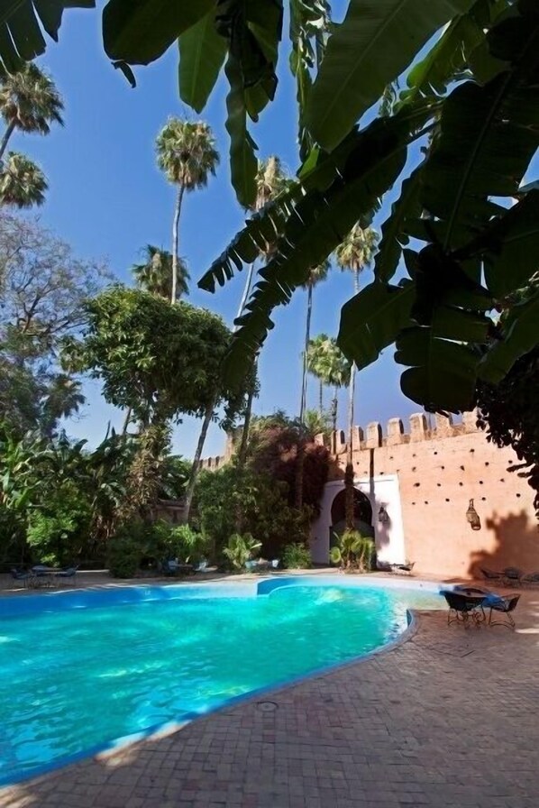 Una piscina al aire libre, sombrillas, tumbonas