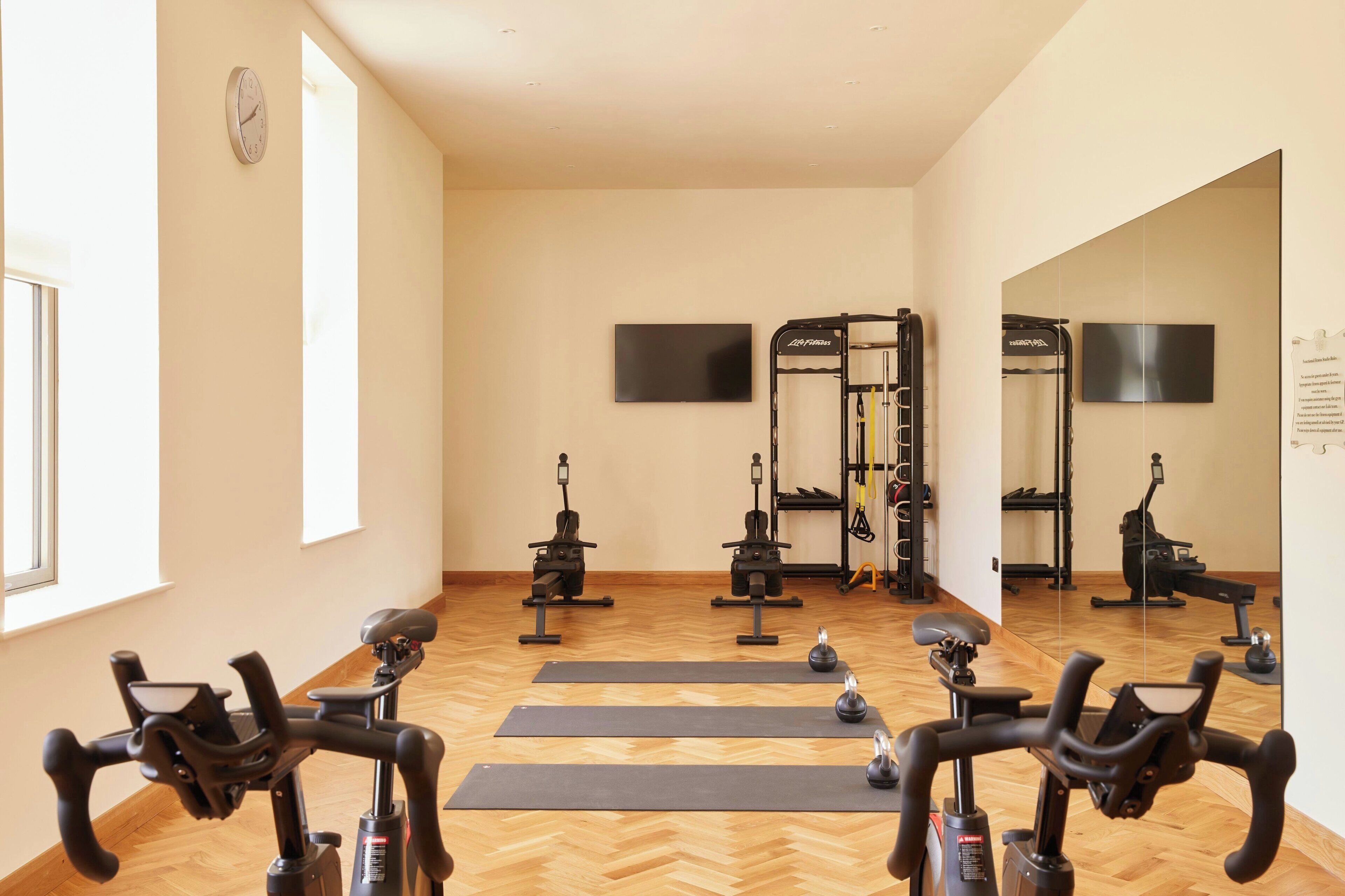 A gym with stationary bikes, exercise equipment, and a mirror.