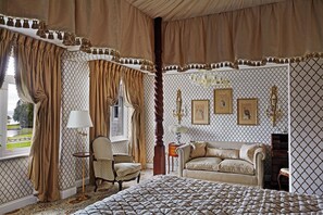 Classic design bedroom with a large bed, sitting area, and decorative chandelier.