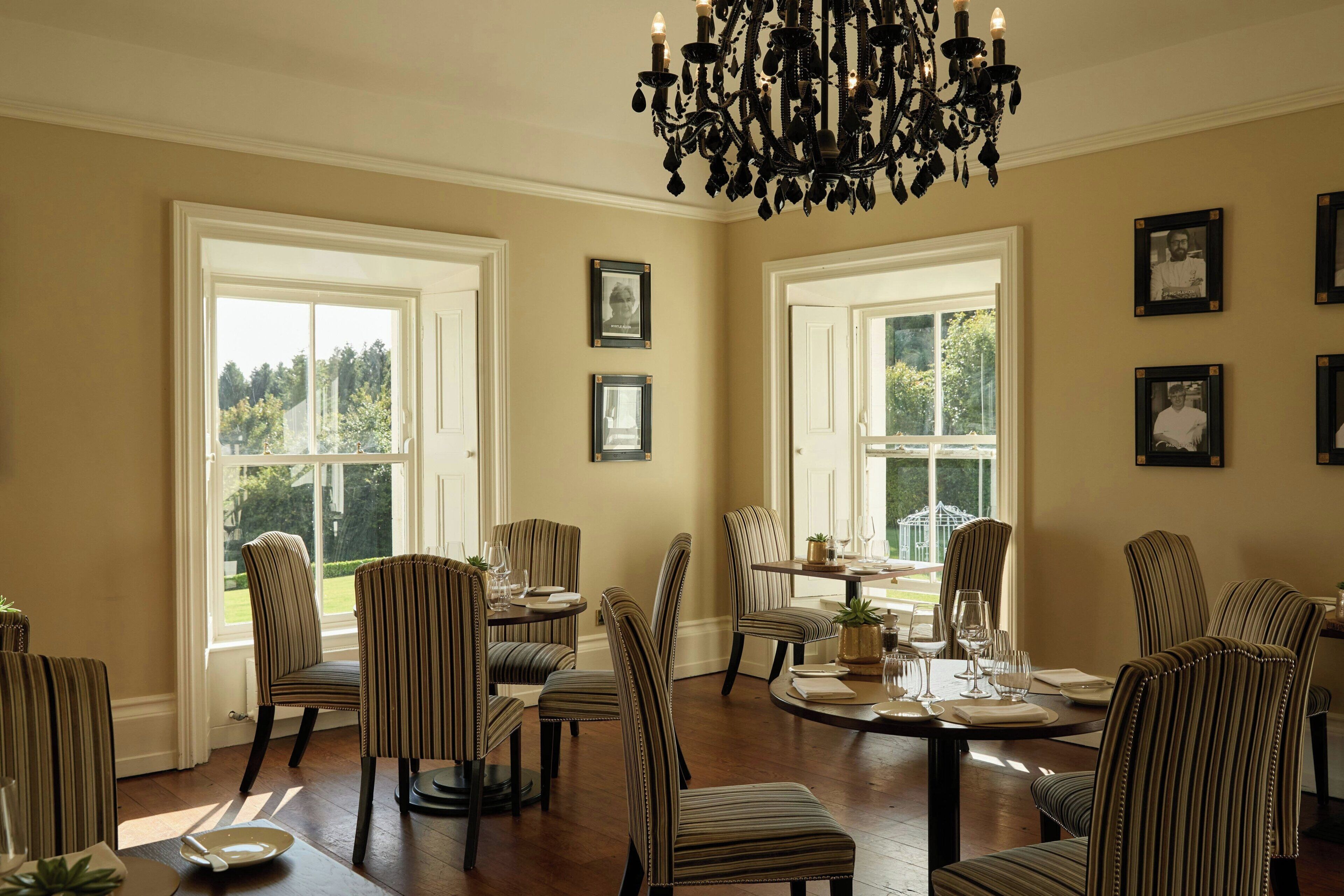 A dining room with striped chairs, a chandelier, and framed pictures on the walls.