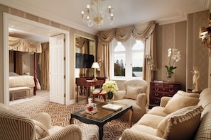 Relax in a spacious room with a large bed, sofa, and dining area, surrounded by tasteful decor and a beautiful view.