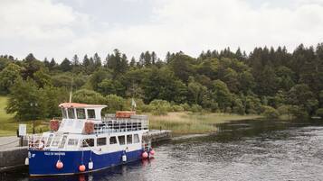 A boat named "Isle of Inisfree" docked at a pier with a forested shoreline in the background.