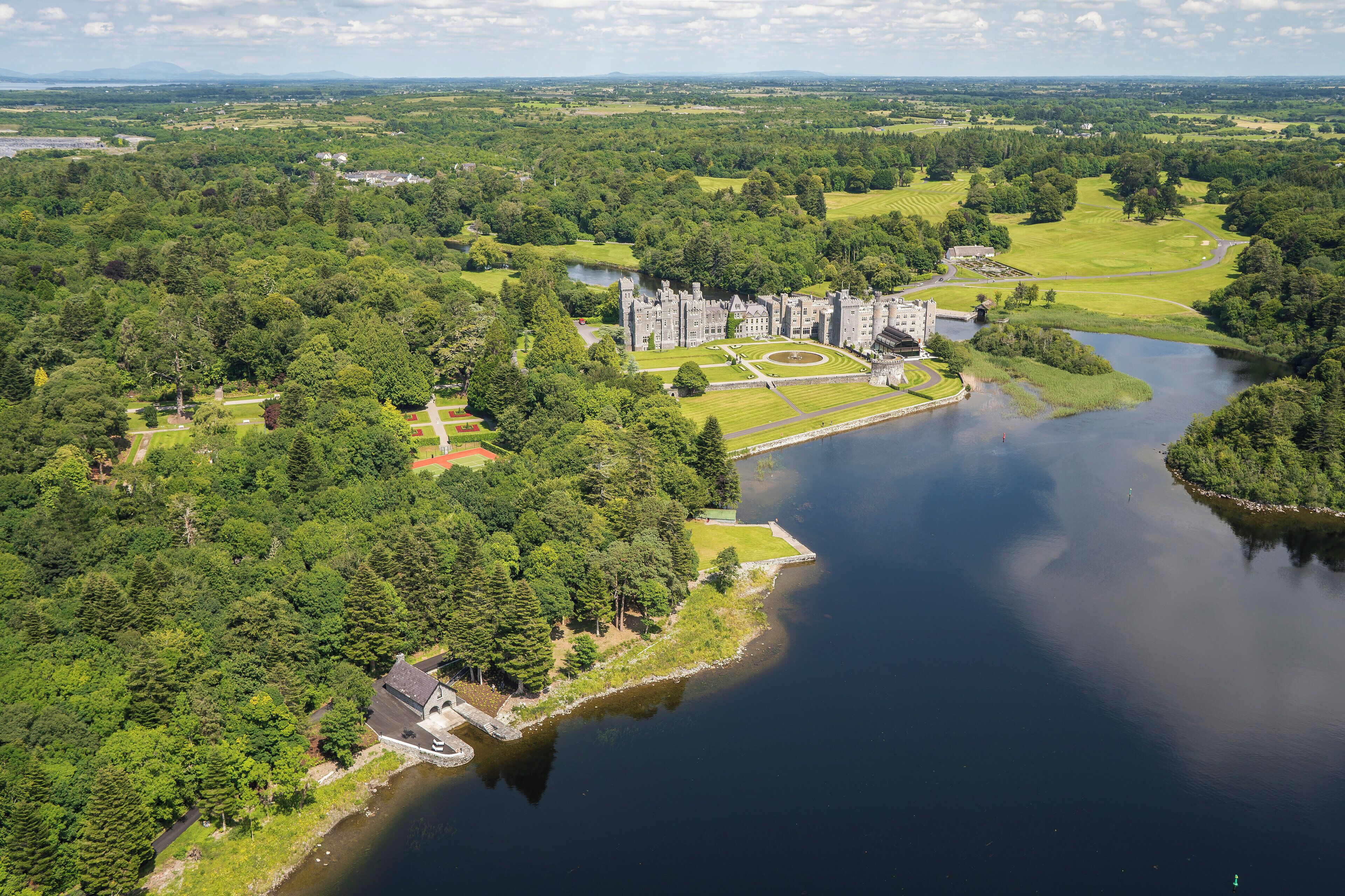 An aerial view of a castle surrounded by lush greenery and a lake.