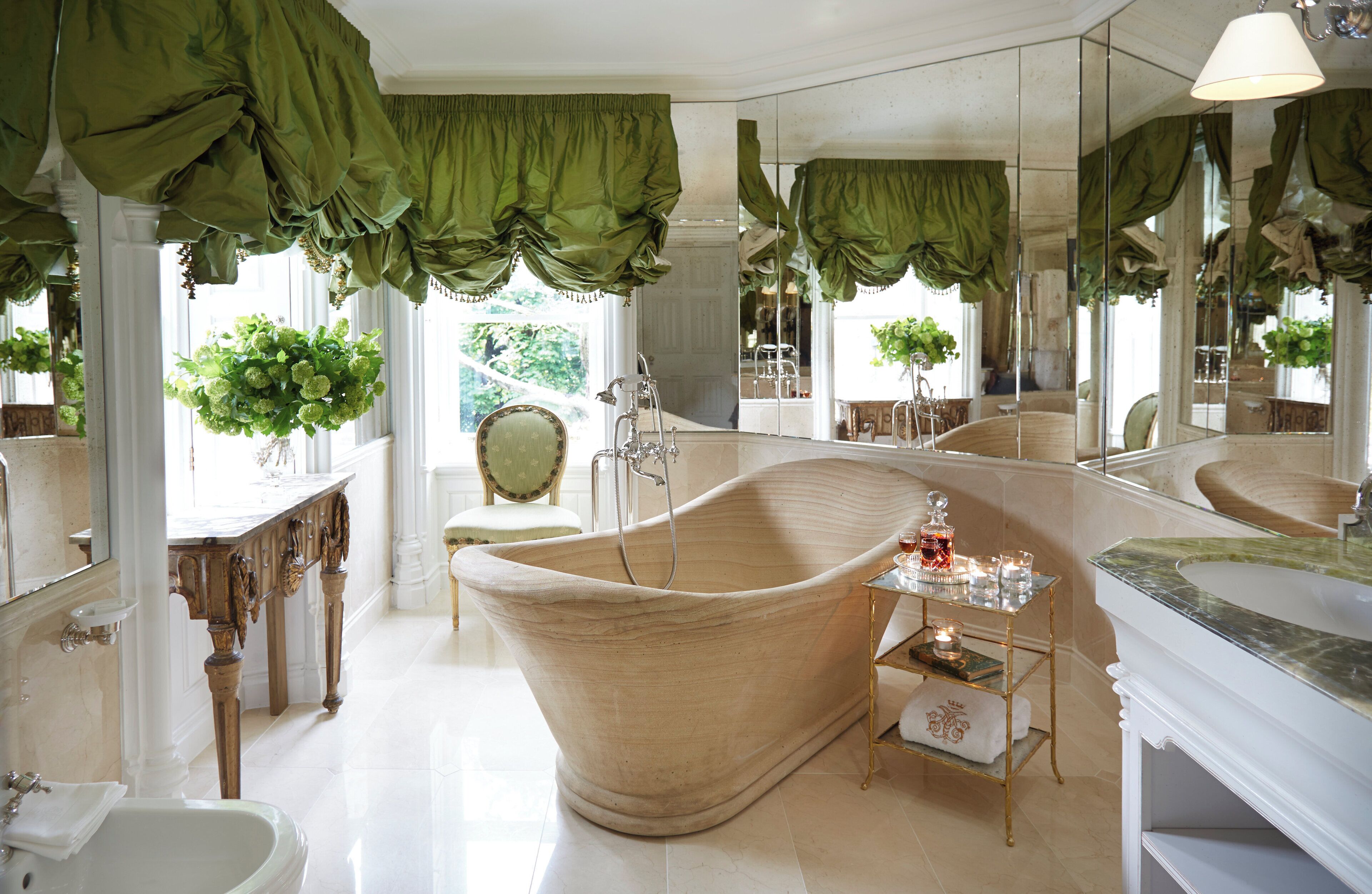A classic bathroom with a freestanding bathtub, a large mirror, and a vanity with a marble countertop.