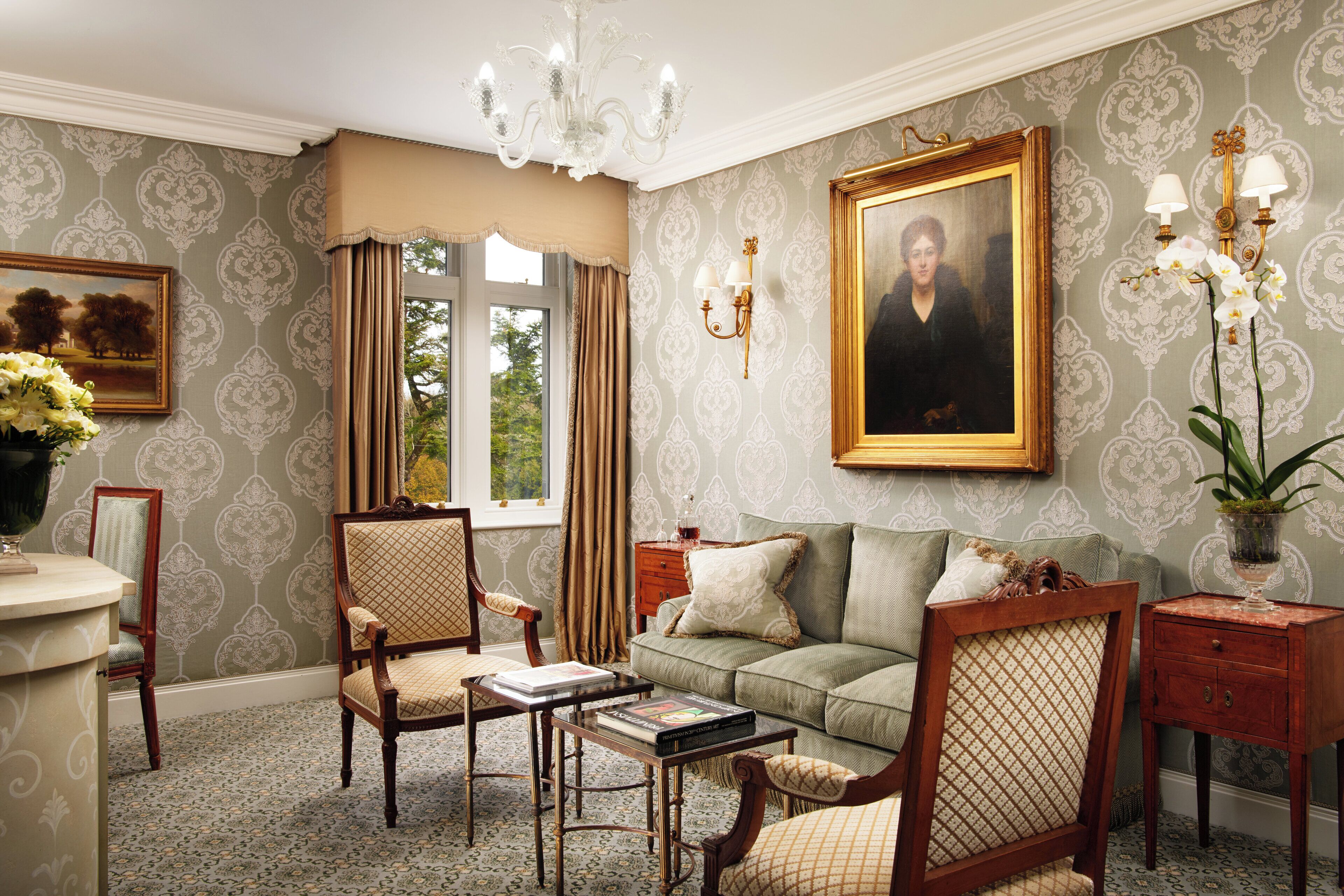 Ein traditionell eingerichteter Raum mit Sofa, Stühlen, einem Tisch, einem Gemälde und einem fenster mit Vorhängen.