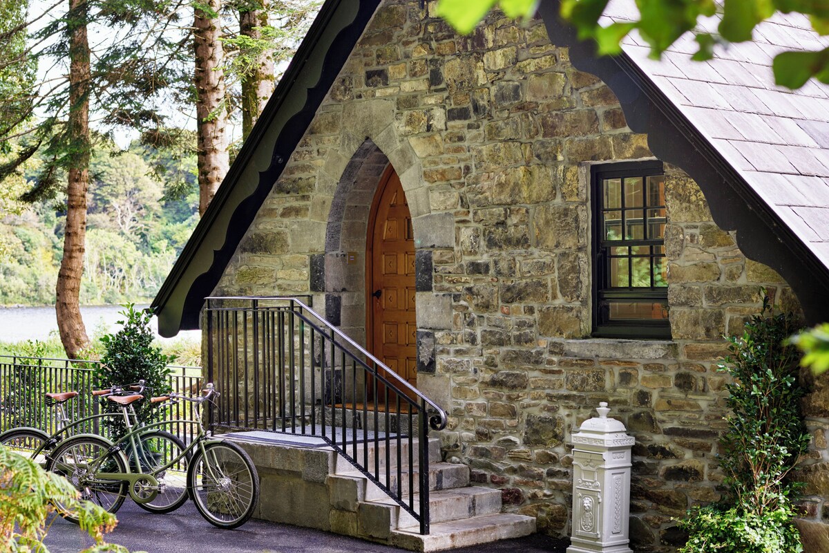A stone building with a wooden door and a small porch. There are bicycles parked in front.
