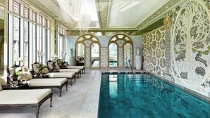 Une piscine intérieure luxueuse, agrémentée de motifs décoratifs sur les murs et dotée d’espaces de détente.