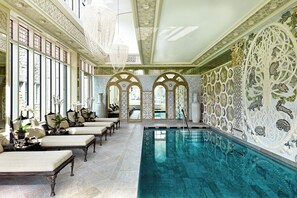 Relax by the pool surrounded by intricate artwork and lounge chairs.