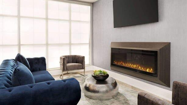 A modern living room with a large sofa, a fireplace, and a flat-screen TV mounted on the wall.