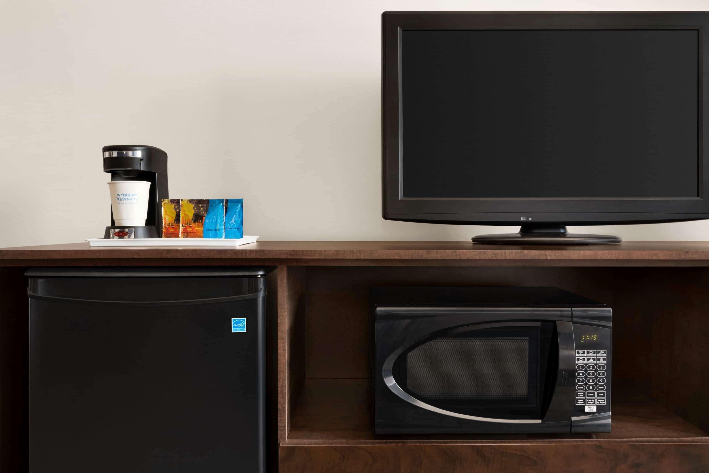 A kitchenette with a coffee maker, microwave, and refrigerator.