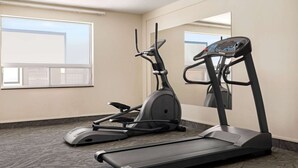 A hotel room with a treadmill and elliptical machine.
