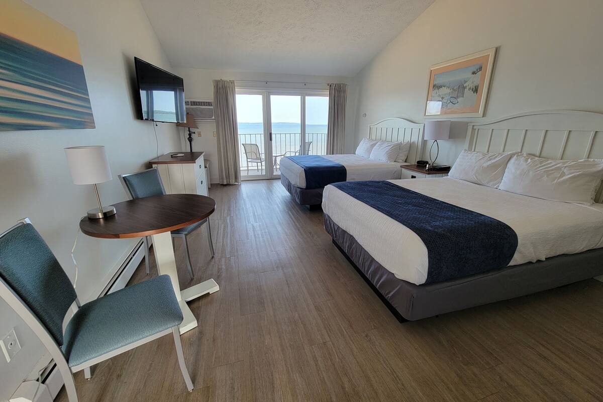 A hotel room with a bed, a desk, a chair, a TV, and a balcony with a view.