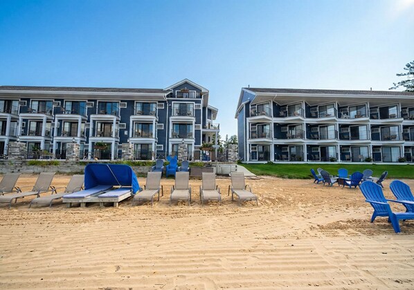 A beachfront hotel with multiple balconies, sun loungers, and a sandy beach area. - Pointes North Beachfront Hotel – 2 Person Spa Tub Studios (Traverse City)