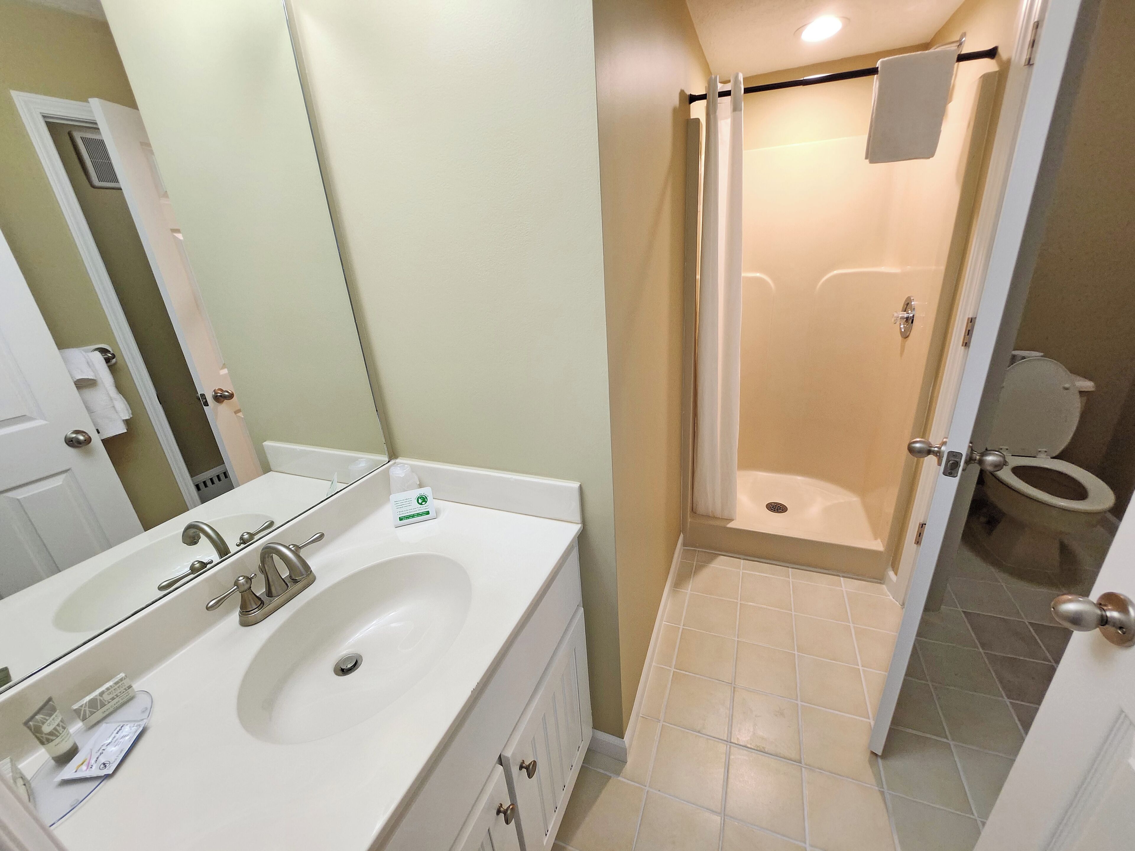 A bathroom with a double sink, a shower, and a toilet.