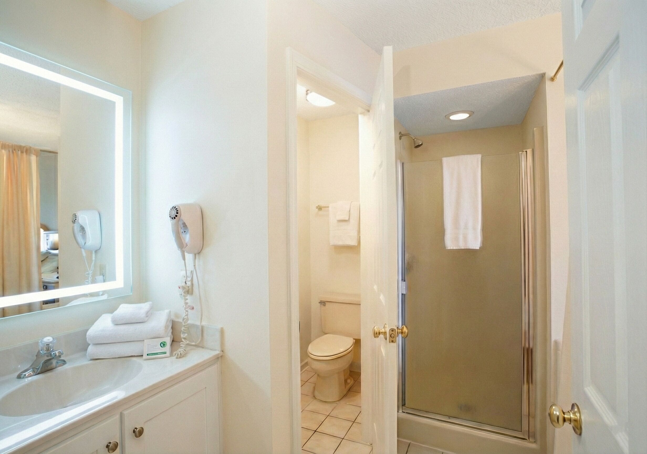 Une salle de bain équipée d’un lavabo, d’un miroir, d’un sèche-cheveux et d’un espace douche.